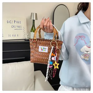 Detailed texture of brown woven beach bag with bamboo handle and colorful charms