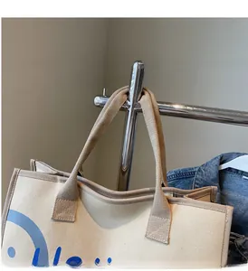 Detailed shot of reinforced straps and thick canvas texture on a beige tote bag