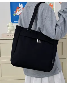 Close-up of black canvas tote bag showing dual zipper closure and brand side label