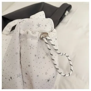 Detailed macro of white textured tote with silver stars and woven drawstring detail