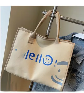 Detail of canvas tote bag with blue Hello text and colorful smiley faces on beige fabric