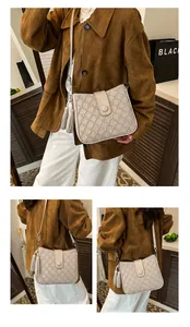 Détail du sac seau beige avec texture matelassée ondulée et pompon en cuir élégant