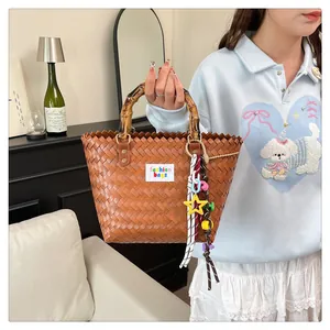 Close-up of brown woven bag with bamboo handles and colorful fashion charms