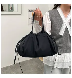 Dettaglio della borsa a secchiello nera con coulisse e design plissettato in nylon