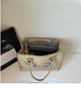 Detail showing the large interior capacity of this beige canvas tote with laptop and bottle