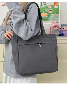 Large dark grey canvas tote bag with side pockets shown in a casual lifestyle setting