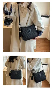 Détail d'un sac seau noir tissé avec pompon élégant et bandoulière réglable en cuir
