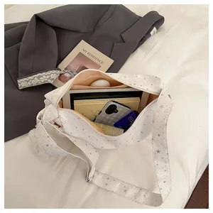 Spacious white star print crescent bag interior holding tablet, book, and phone