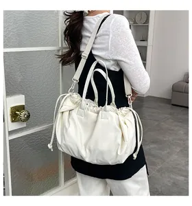 Dettaglio della borsa beige minimalista con coulisse, pieghe e tracolla larga