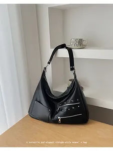 Detail of vintage black hobo bag with silver rivets and zippers on a wooden table