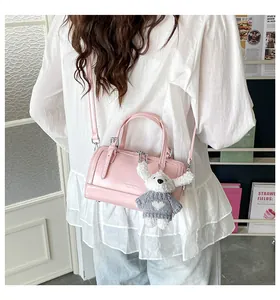 Detail of light pink cylinder bag with silver hardware and a cute white puppy pendant