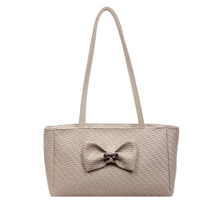 Beige woven tote bag with a centered bow accent and slim handles for a relaxed commute