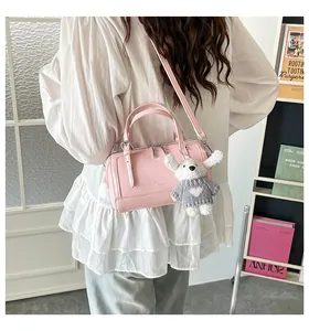 Pink Boston bag detail featuring plush dog charm and detachable shoulder strap on model