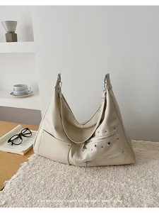Macro detail of creamy beige vintage shoulder bag with silver rivets and zipper pockets