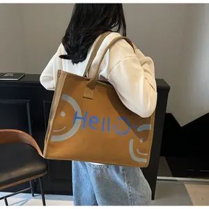 Close-up of mustard canvas tote bag featuring blue Hello text and a grey smiley face print