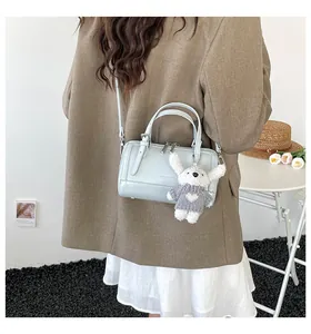 Detail of light blue boston bag with plush bunny charm and adjustable shoulder strap