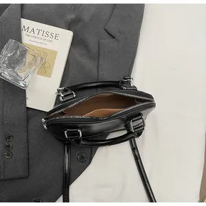 Top view of black shell bag showing brown fabric interior lining and inner pocket detail