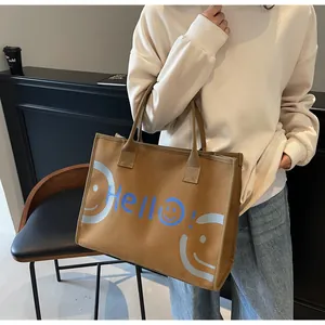 Detail of a large brown canvas tote bag with a blue Hello and smiley face pattern