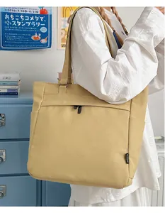 Detail view of khaki canvas tote bag featuring front zipper pocket and side pocket