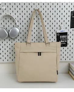 Detail of beige canvas tote bag with large front double-zipper pocket and side pockets