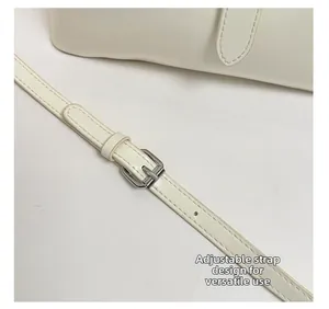 Detail of adjustable shoulder strap with silver buckle on a white leather bucket bag