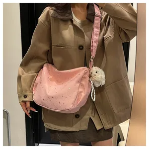 Close-up of pink hobo shoulder bag with silver star patterns and cute plush keychain
