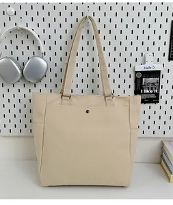 Detail of minimalist canvas tote bag with front pocket and side compartments in off-white