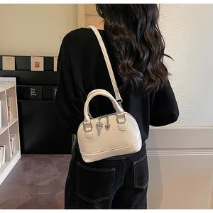 Detail of white shell-shaped handbag featuring silver heart and key charms on handle