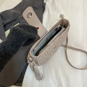 Sac seau beige à texture tissée avec pompon et compartiment intérieur spacieux pour femme
