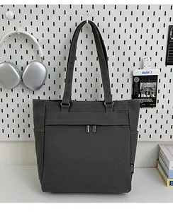Detail view of deep gray canvas tote bag featuring metal buckles and a side pocket