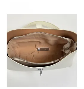 Top view of white bucket bag interior with brown fabric lining and silver metal zip pocket