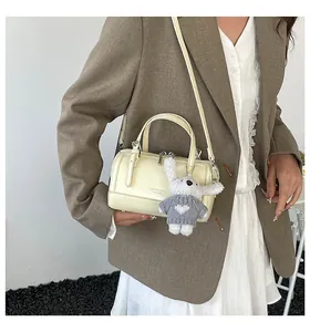 Creamy white Boston bag with cute rabbit pendant shown in a stylish street style pose