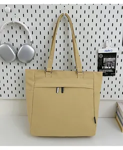Detail of a khaki canvas tote bag with side pockets and a secure metal zipper closure