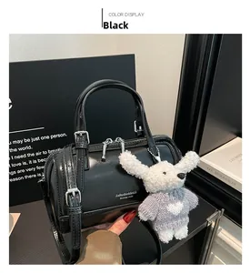 Detail of black faux leather Boston bag featuring silver hardware and plush bunny pendant
