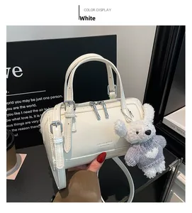 Detailed view of a white cylindrical handbag featuring a cute plush bear charm accessory