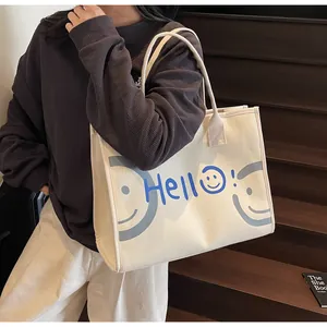 Off-white canvas tote bag with Hello print and smiley face shown in a casual lifestyle setting