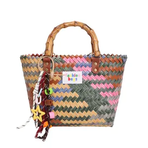 Colorful woven beach tote with bamboo handle and star charm accessory on white background