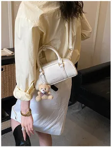 Détail d'un sac à main blanc en cuir plissé avec bandoulière et charmant pendentif ours