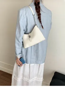 Lifestyle shot of white crescent shoulder bag with silver chain strap on model