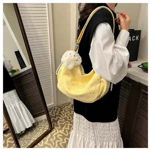 Detail of yellow crescent shoulder bag featuring star prints and plush sheep charm