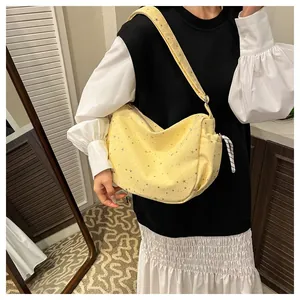 Detail of yellow crescent tote bag with silver star patterns and adjustable strap