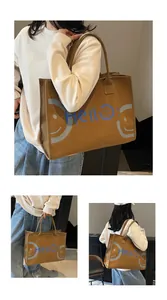 Detail view of large brown canvas tote bag with blue Hello text and smiley face graphic