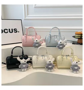 Detail of five colorful mini boston bags with cute plush bunny charms on tiered display