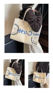 Detailed view of canvas tote bag featuring blue Hello text and a grey smiley face print