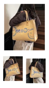 Close-up of beige canvas tote bag featuring blue Hello lettering and smiley face detail
