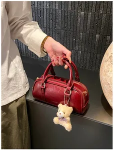 Détail d'un sac cylindrique rouge foncé en cuir brillant avec fermeture éclair dorée