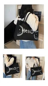 Detail view of a large black canvas tote bag featuring a white Hello smile graphic