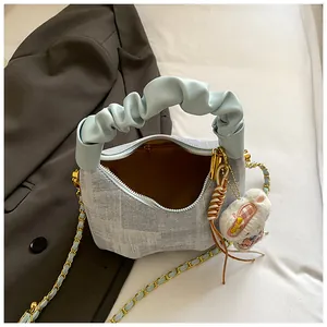 Close-up of light blue textured handbag with cloud handle and cute plush bunny charm