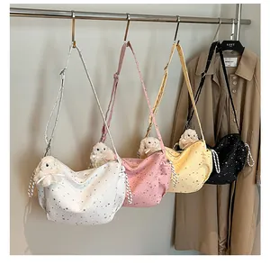 Detail of four colorful star-printed canvas crossbody bags with plush bunny charms