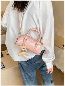 Sac cylindrique rose plissé avec poignées et breloque ours porté par un mannequin